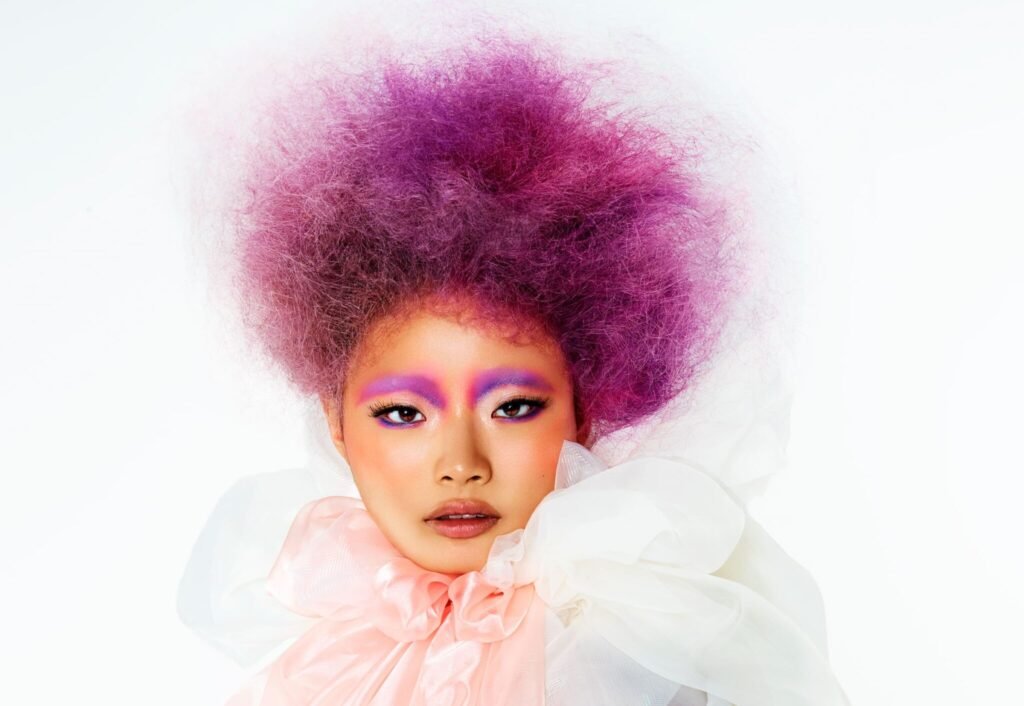 A vibrant model showcasing pastel-colored hairstyles from the Dreamsicle Collection, styled by George Alderete and Lisa Vann. The look features soft, creamy hues and textured fashion by Lisa Vann.