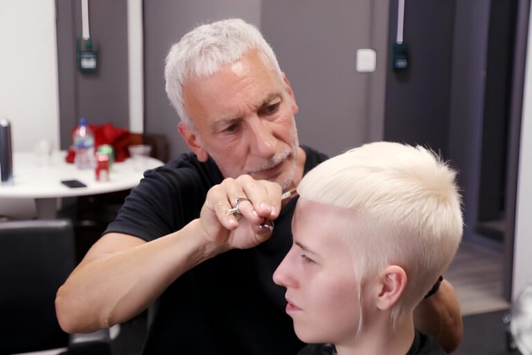 Short platinum-blond crop with a sharp, straight fringe line and softly spiked top being cut with scissors by Akin Konizi